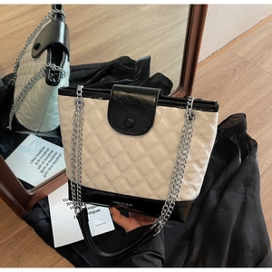 Detail of contrast color quilted bucket bag with chain strap and metallic magnetic closure