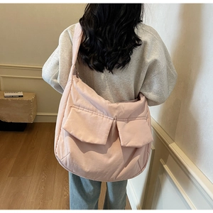 Detail of pink quilted crossbody bag with dual pockets shown on model's shoulder