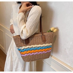 Detail of multi-color woven tote bag with textured stripes and brown leather straps