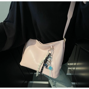 Detail of pink leather bag with embossed text and cute cartoon dog and lollipop charms