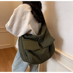 Close-up of olive green quilted crossbody bag with large pockets on model