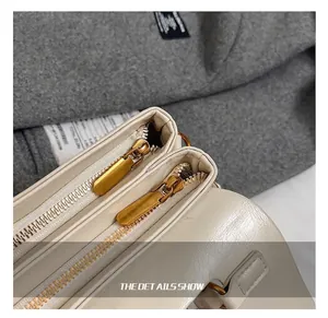 Close-up of premium gold-tone zippers and smooth leather texture on a beige shoulder bag