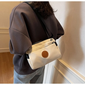 Vue détaillée d'un sac bandoulière blanc en nylon avec bordure noire et logo en cuir