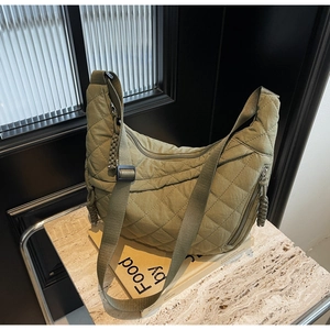 Detailed close-up of olive green quilted hobo bag featuring wide nylon shoulder strap
