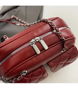Close-up of wine red quilted leather bag showing silver double zippers and fine stitching