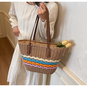 Detail of handwoven straw tote bag with multi-colored wave patterns and leather straps