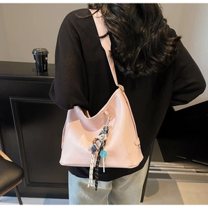 Detailed view of pink shoulder bag with cute bear charm and woven rope accessories