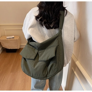 Detail of dark olive green quilted tote bag with large front pockets worn on shoulder