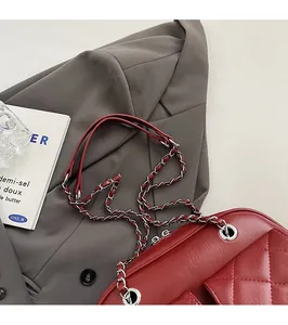 Detail of burgundy quilted rhomboid pillow bag with silver chain strap on a blazer