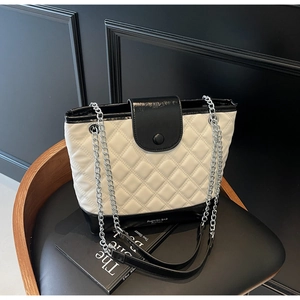 Close-up of quilted bucket bag with silver chain strap and black and white contrast leather