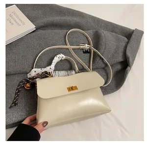Detail view of cream white tote bag with silk scarf handle and golden clasp lock