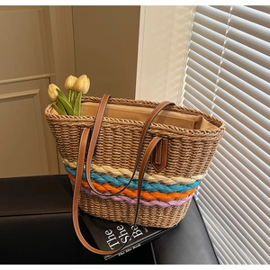 Detail of woven straw tote bag featuring colorful stripes and brown leather handles