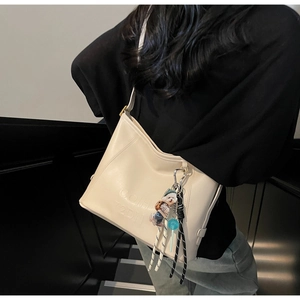 Detail of cream hobo bag with 3D embossed text and cute colorful cartoon pendants
