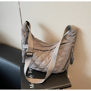 Detail of quilted rhombus pattern and woven zipper pull on taupe hobo shoulder bag
