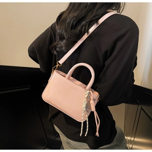 Detail view of pink vintage crossbody bag with braided pendant on leather handle