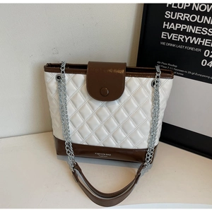 Detail shot of quilted bucket bag featuring white texture and brown leather accents