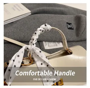 Detail of cream leather handbag with black and white polka dot scarf wrapped on top handle