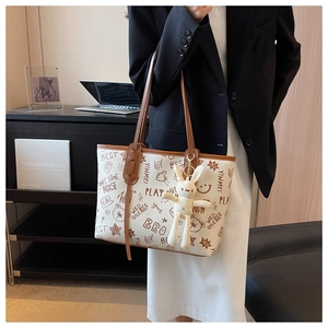 Detail of printed tote bag with plush rabbit charm and stylish graffiti patterns