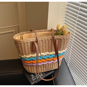 Detail of colorful woven straw tote bag with multi-color stripes and leather handles