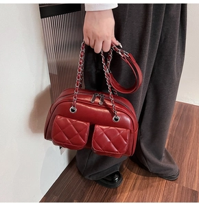 Close-up of wine red quilted handbag featuring silver chain and dual front pockets