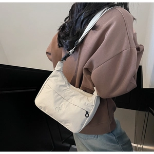 Dettaglio della borsa a tracolla in nylon beige con logo ricamato e tracolla regolabile