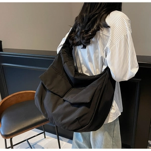 Detail of black oversized tote bag with dual front flap pockets and soft fabric texture