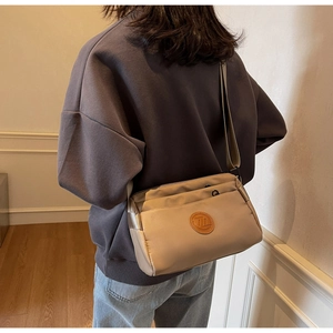 Détail du sac bandoulière en nylon beige avec double fermeture éclair et sangle