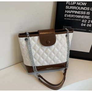 Detail of quilted bucket bag with contrasting brown leather trim and chain strap