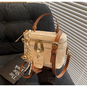 Détail du sac boîte en similicuir crème avec poignée marron contrastée et finitions dorées