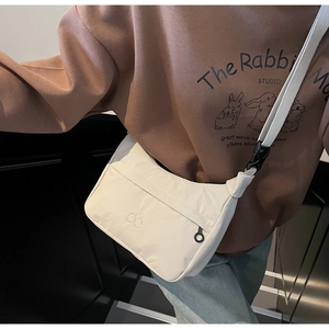 Dettaglio della borsa a tracolla minimalista in nylon beige con tasca a zip e fibbia