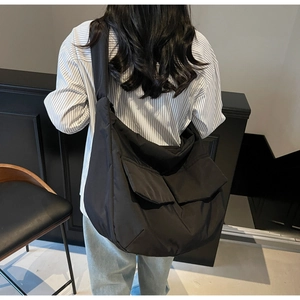 Rear view of a black oversized nylon tote bag showing its scale on a model