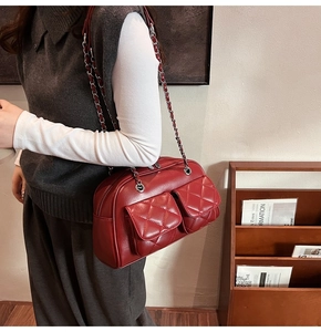 Macro view of burgundy quilted crossbody bag with silver chain strap on model