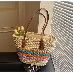 Detail of hand-woven straw tote bag with multi-color accents and brown leather straps