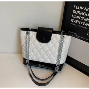 Close-up of black and white quilted bucket bag with silver chain and fashion text