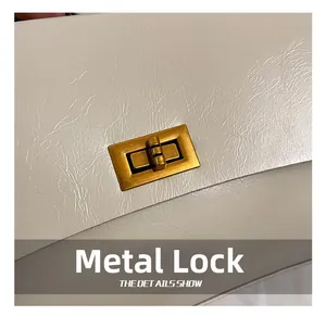 Close-up of golden hardware turn-lock on textured white synthetic leather handbag