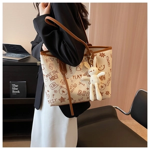Detail of a large white tote bag with brown graffiti patterns and a cute rabbit charm