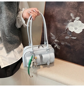 Detail of light blue patent leather shoulder bag with pockets and cute bear pendant