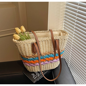 Detailed close-up of straw beach tote with colorful woven bands and leather handles
