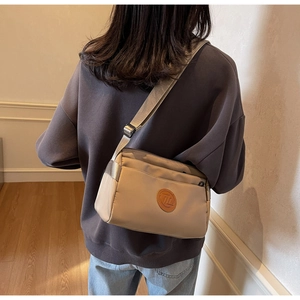 Détail d'un sac à bandoulière en nylon beige avec sangle réglable porté par mannequin