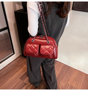 Detail of red quilted leather shoulder bag with dual pockets and silver chain straps
