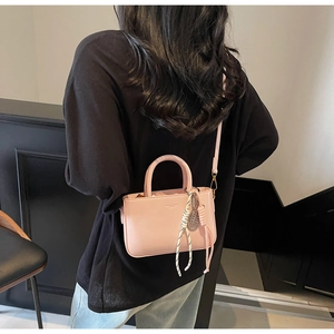 Close-up of pink leather handbag with striped silk scarf detail and detachable shoulder strap