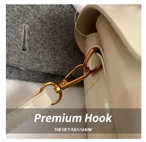 Macro shot of high-quality gold metal hook and white glossy leather finish on shoulder bag
