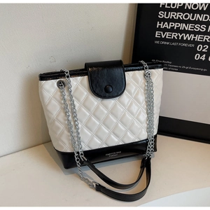 Detail of white quilted bucket bag with black leather base and silver chain strap