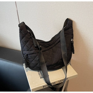 Detail of the black quilted crossbody bag showing large diamond stitching and nylon strap