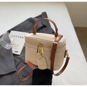 Vue détaillée du sac boîte en cuir crème avec poignée marron et fermeture éclair dorée