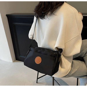 Gros plan d'un sac bandoulière en nylon noir avec sangle réglable porté par un mannequin