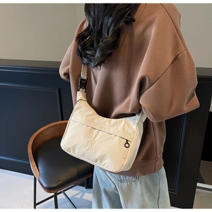 Dettaglio borsa a tracolla beige a mezzaluna con tracolla larga e tasca con cerniera