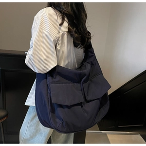 Detail of navy blue large capacity crossbody bag with front flap pockets shown on model