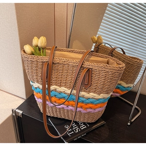 Detail of hand-woven straw tote bag with multi-colored woven straps and slim leather handle