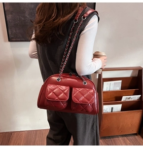 Detailed view of burgundy quilted shoulder bag with chain strap and dual front pockets